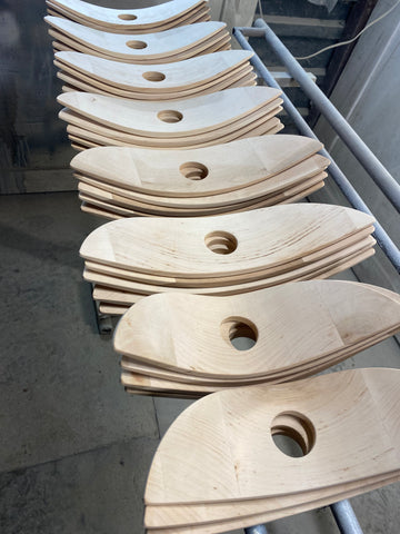 Handcrafted light wood parts for designer lamps, stocked on workshop shelf