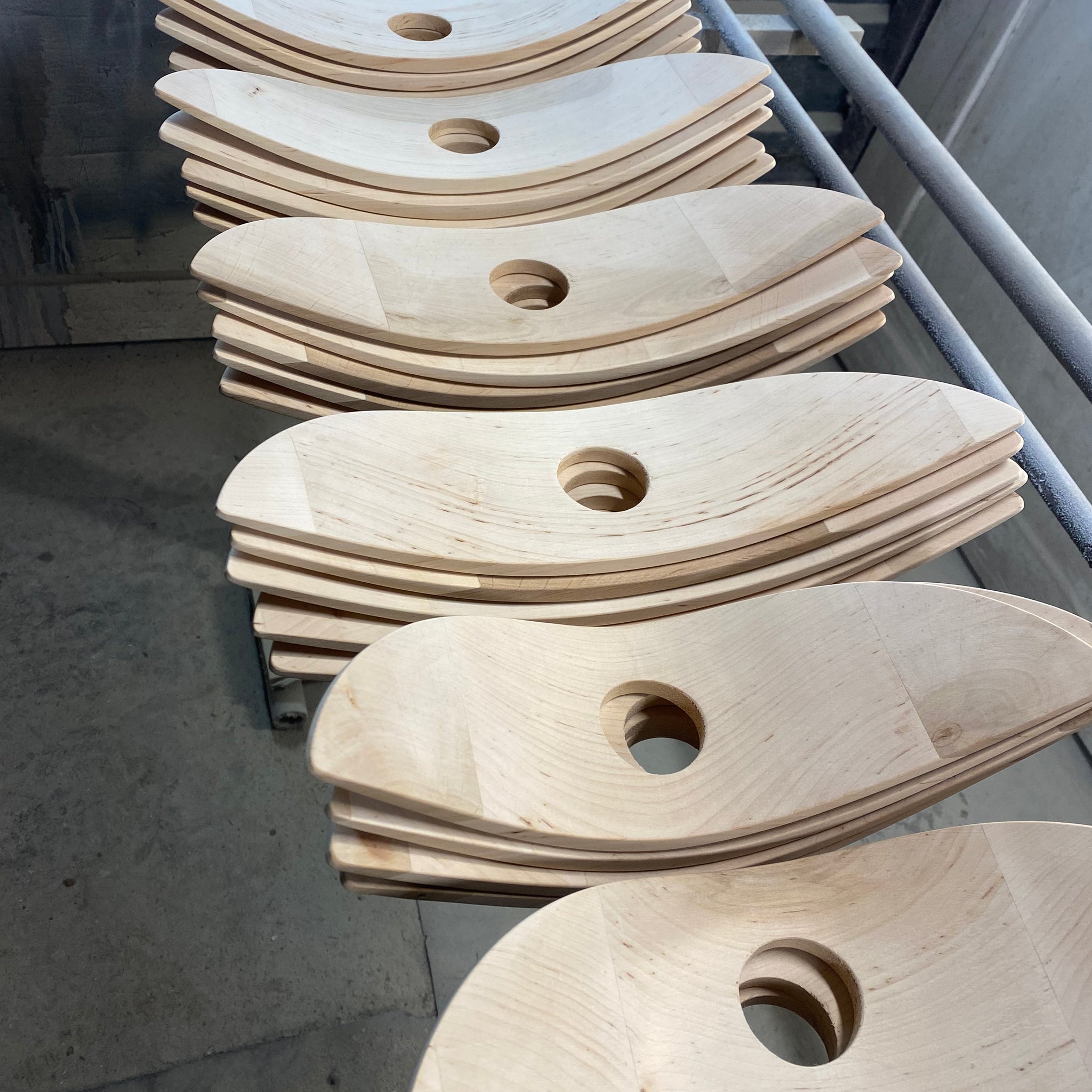 Handcrafted light wood parts for designer lamps, stocked on workshop shelf
